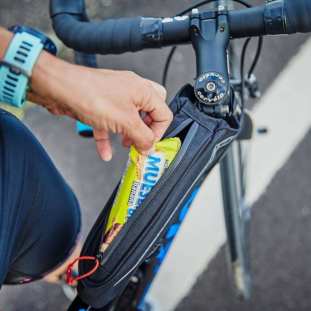 Athlete opening the Zone3 Bento_Box_Bag to take out a snack while cycling. 