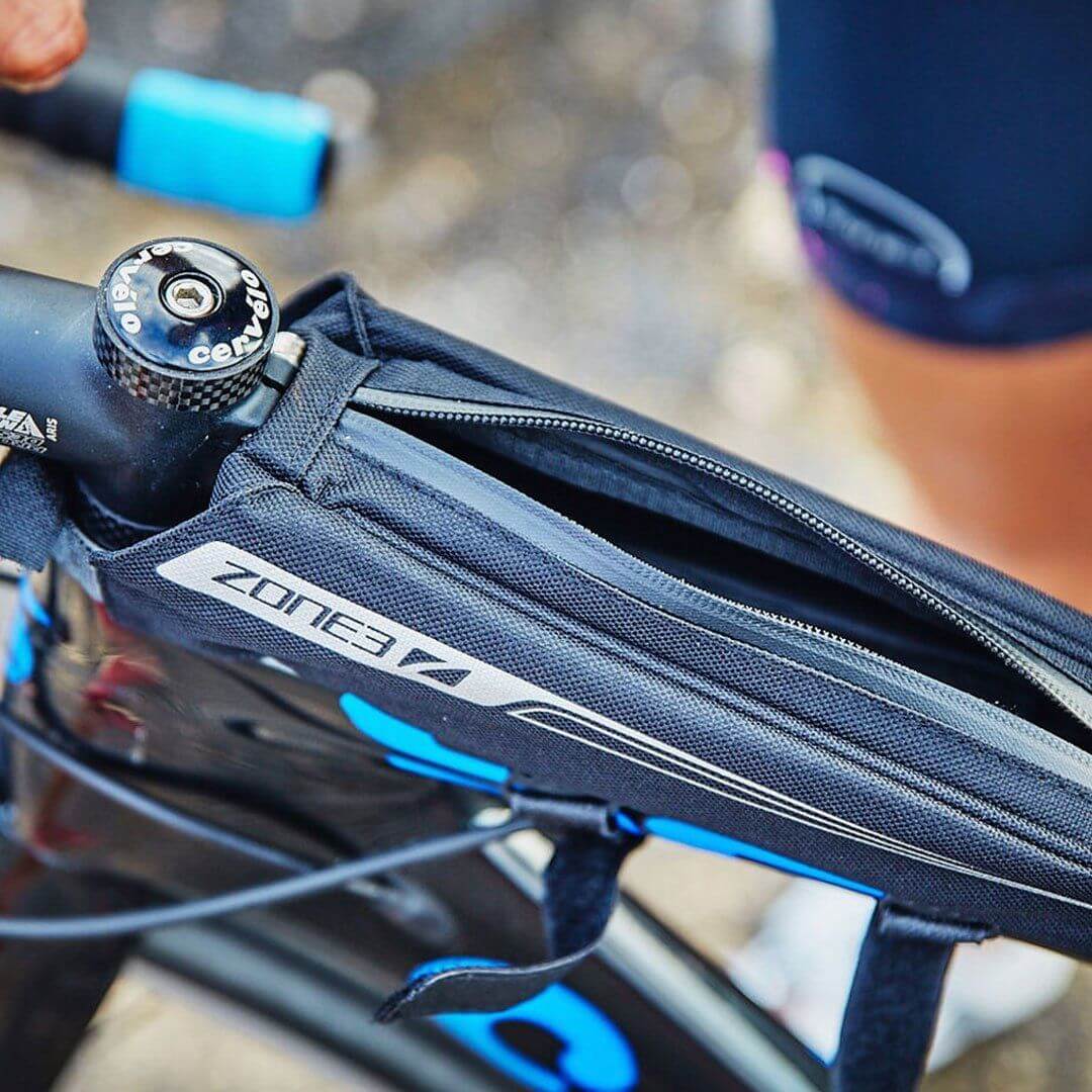 Athlete opening the Zone3 Bento_Box_Bag to take out a snack. the Bento box attached to the bike.