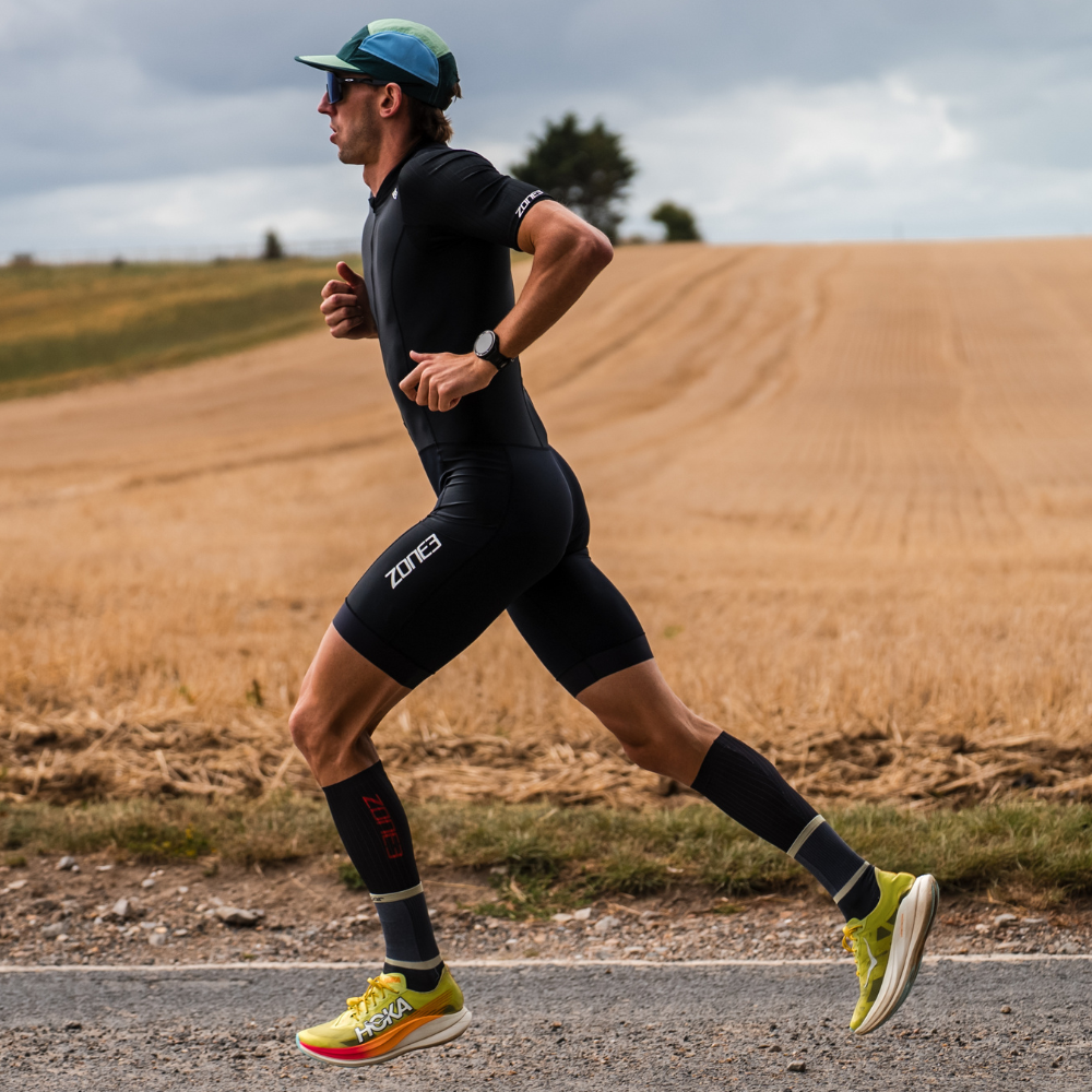 Man running on a road with a field and trees in the background