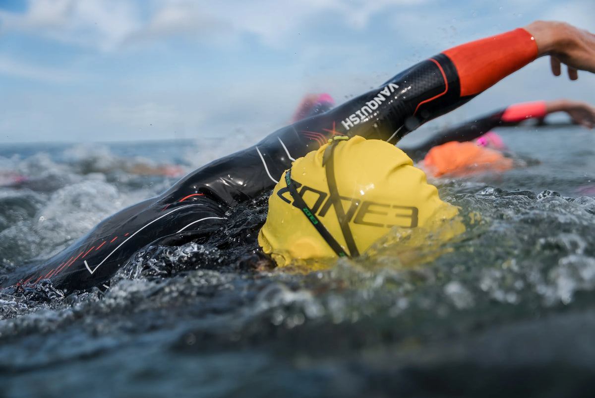 athlete swimming in open water wearing the Zone3 Vanquish-X and yellow swim cap