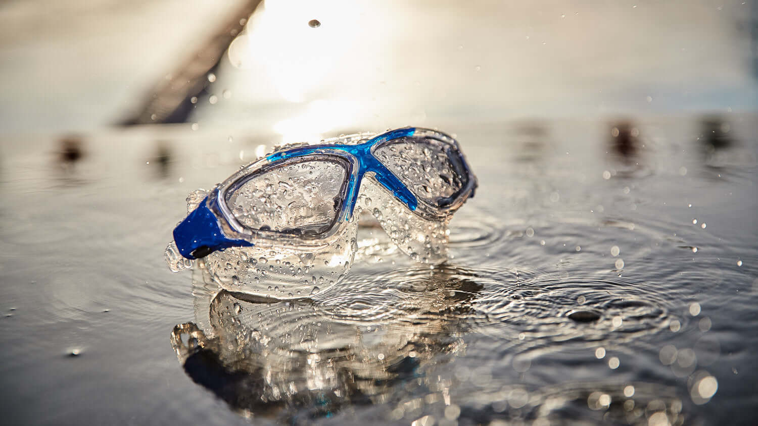 Vision Max Clear Swimming goggles on the surface of water with a blurred background