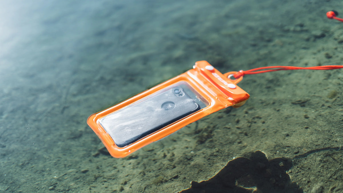 The Zone3 Orange waterproof pouch floating in the water. 