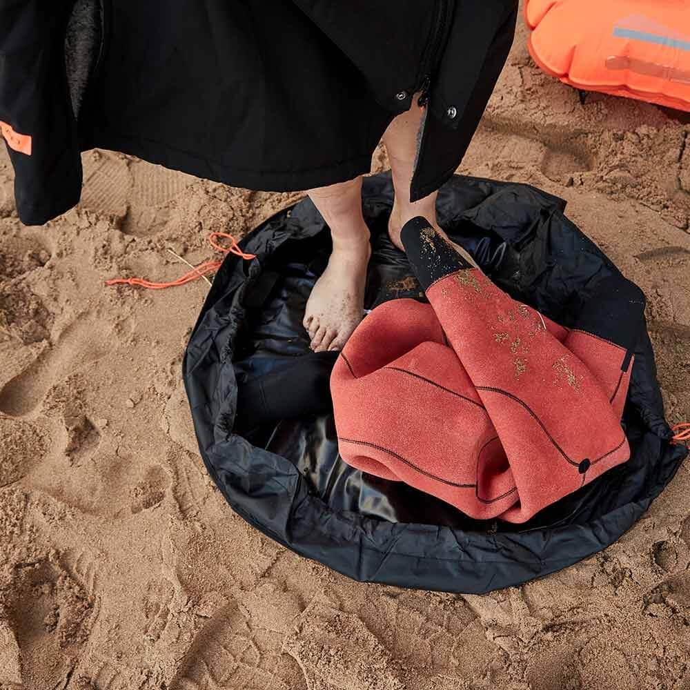 close up of an Athletes feet standing on the Zone3 wetsuit Changing mat at the beach. 