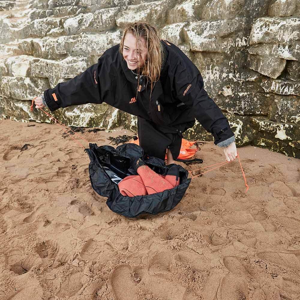 Women Athlete using the string feature on the Zone3 wetsuit changing mat to scope her wetsuit after changing. 