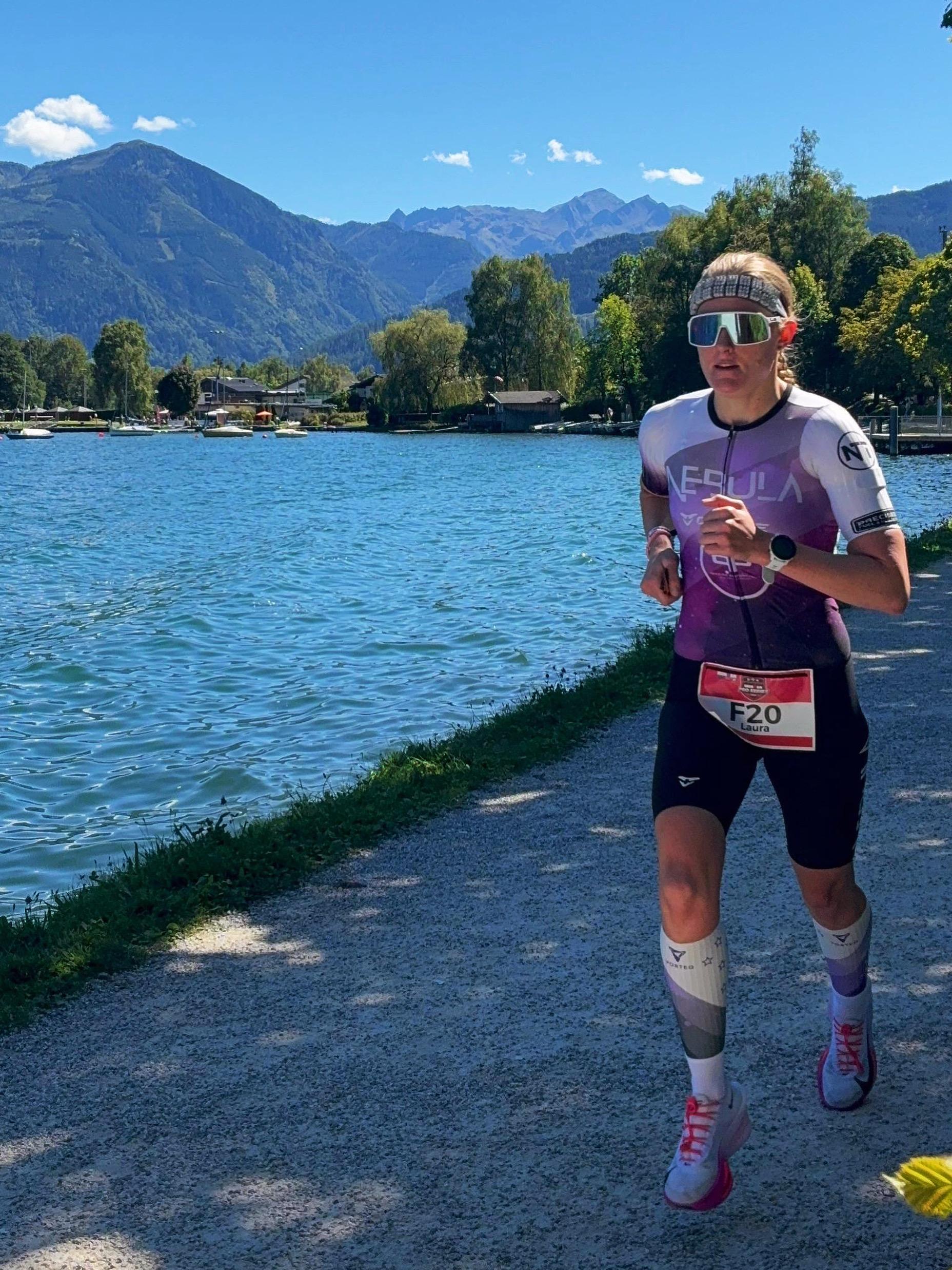 Person running by a lake with mountains in the background