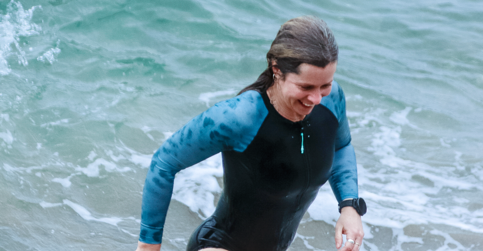 Athlete wearing the Zone3 Women's Long Sleeve Swimsuit at the beach. 