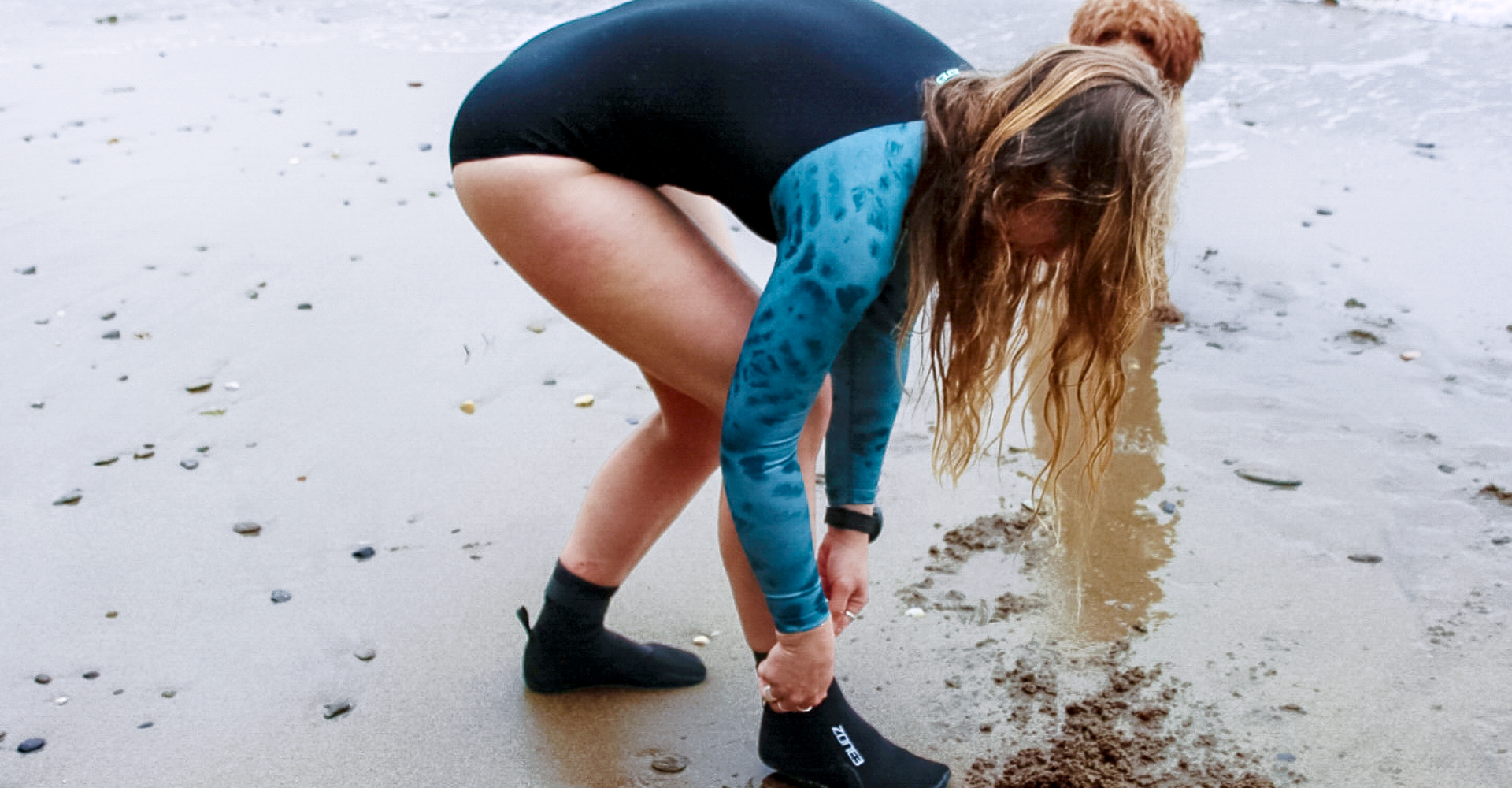 Athlete wearing the Zone3 Women's Long Sleeve Swimsuit at the beach. 
