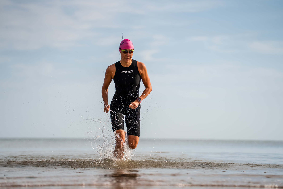 Women running out of the water Wearing the Zone3 Streamline Swimskin.