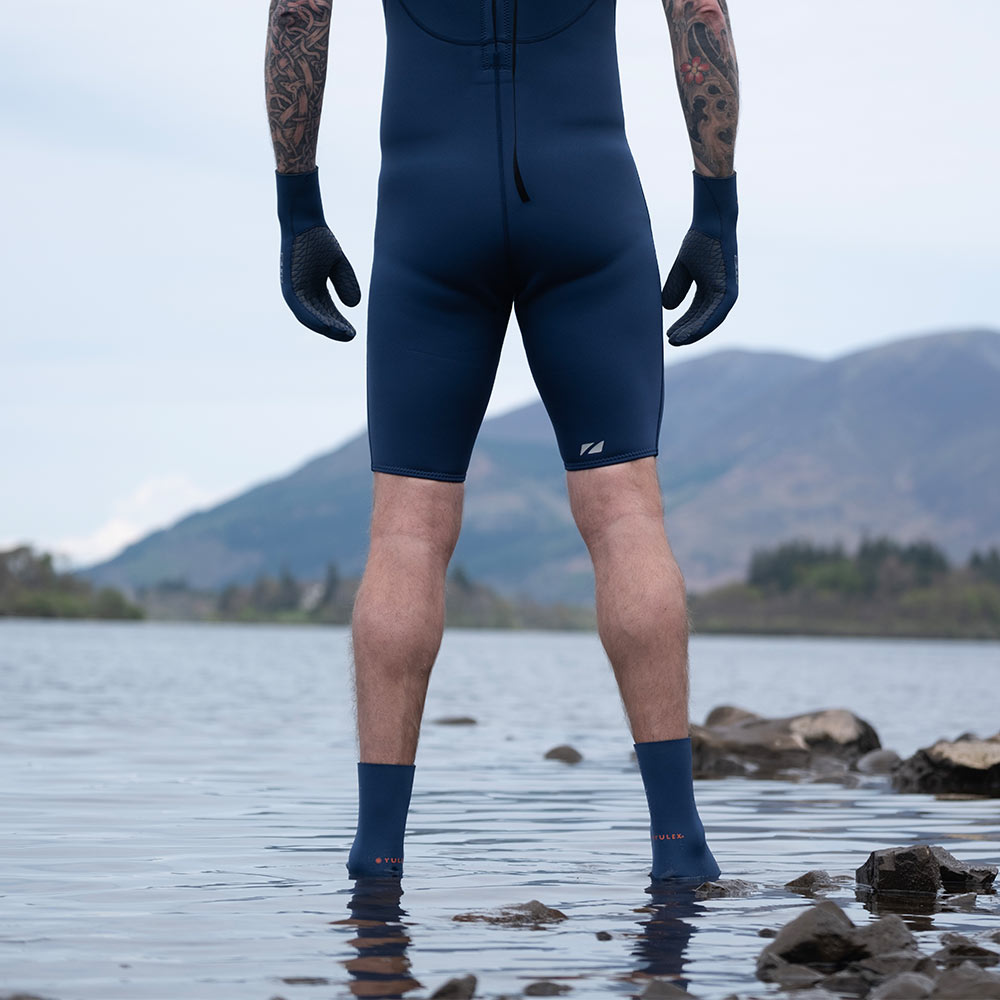 Person wearing a ZONE3 yulex kneeskin standing in water with mountains in the background