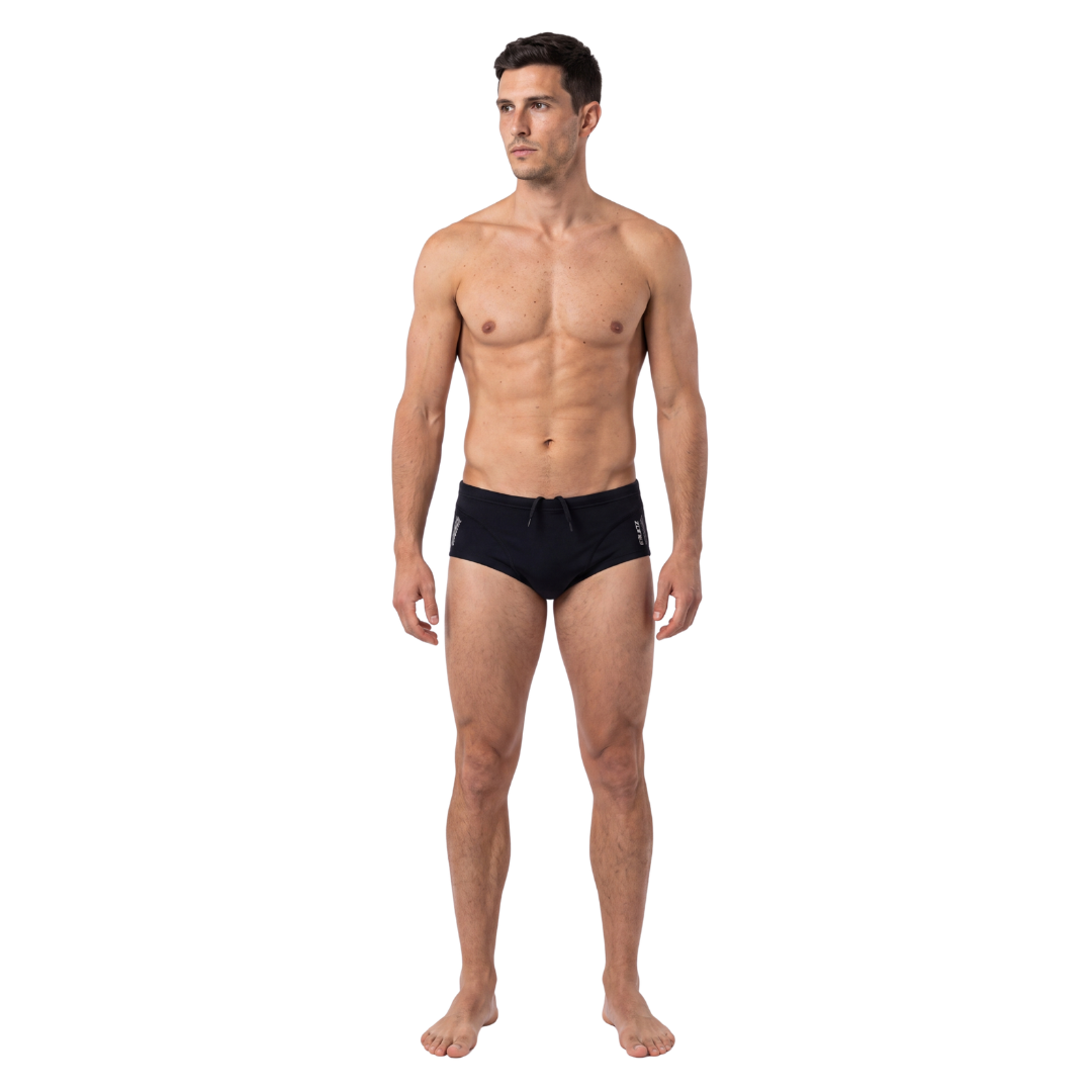 A man modeling black swim briefs against a plain white background.