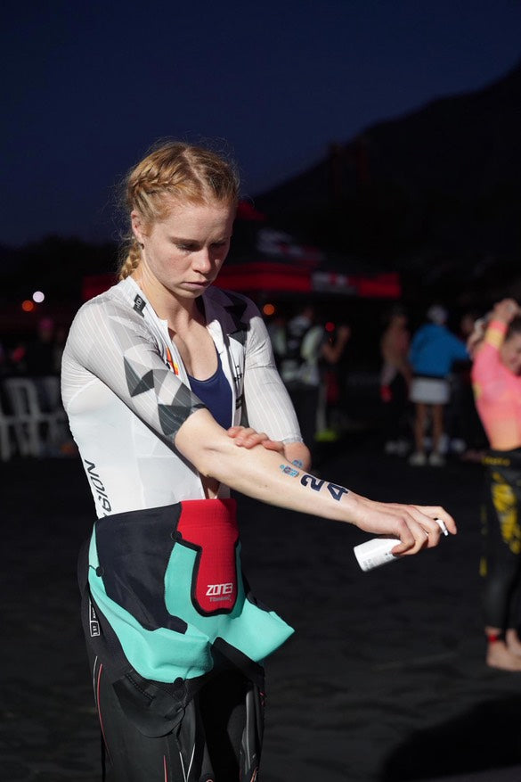 Person applying tape to their wrist at an event with a dark background