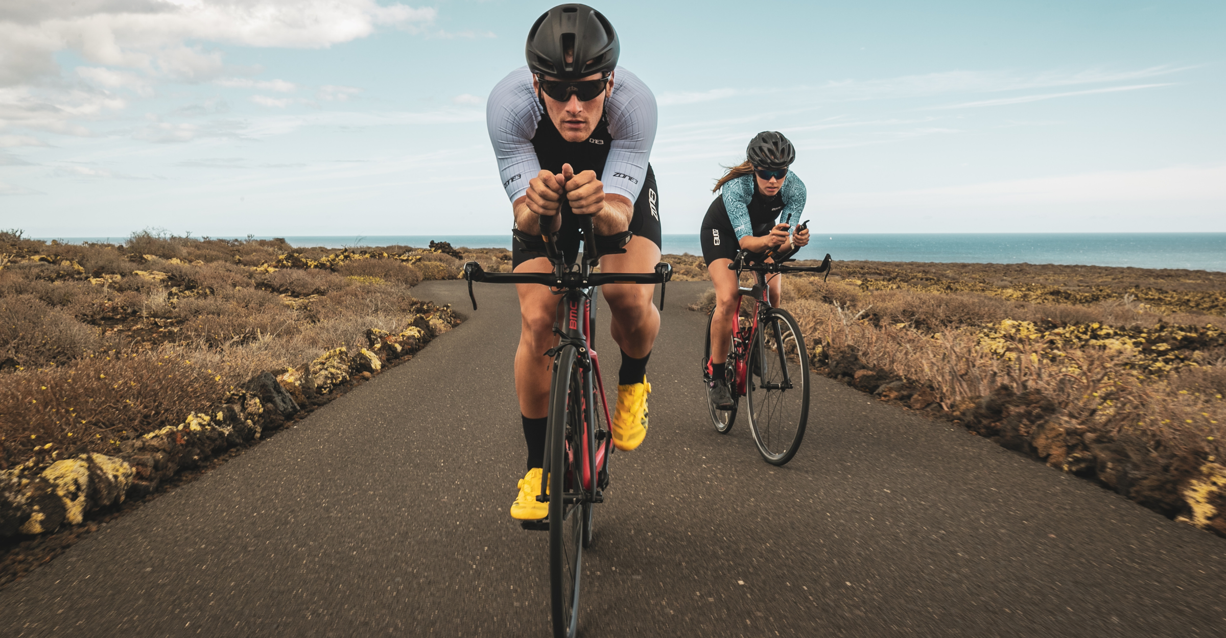 Two cyclists on a road with a scenic background