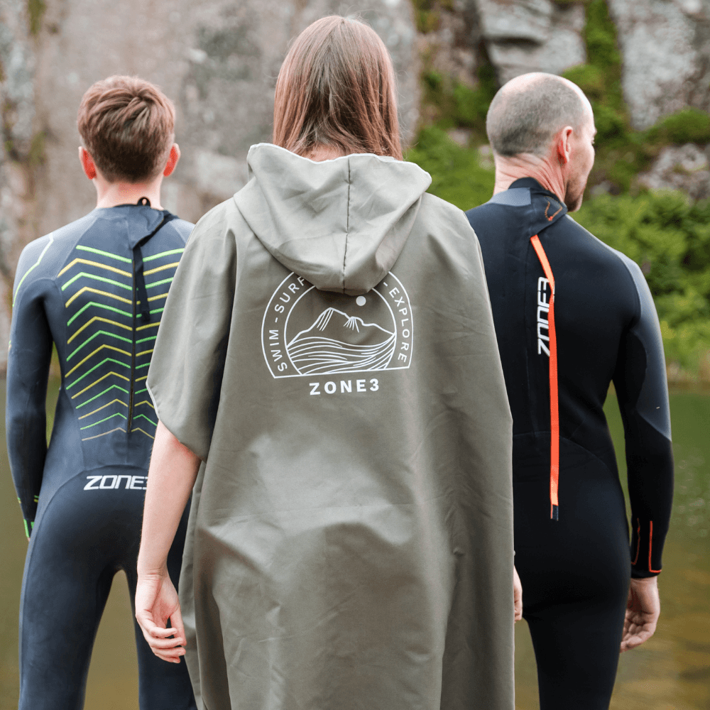 Three people wearing Zone3 wetsuits and a the Microfibre Changing Robe in green from the back.