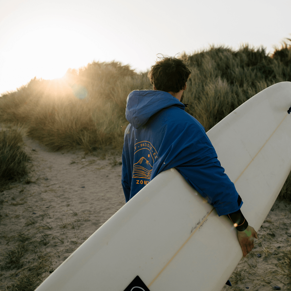 Athlete wearing the blue Thermotech Changing Robe from the back at the beach. 