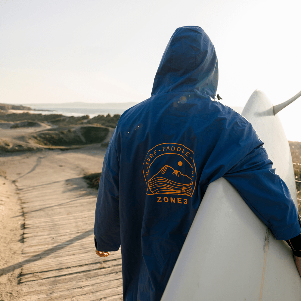 Athlete wearing the blue Thermotech Changing Robe from the back at the beach. 