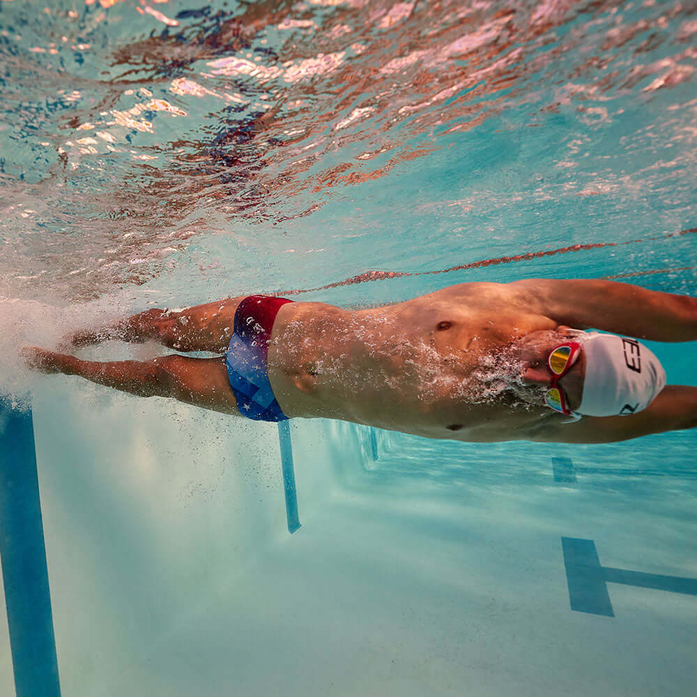Swimmer in water wearing Brief Shorts (USA) designed for performance and style with American Flag colors.