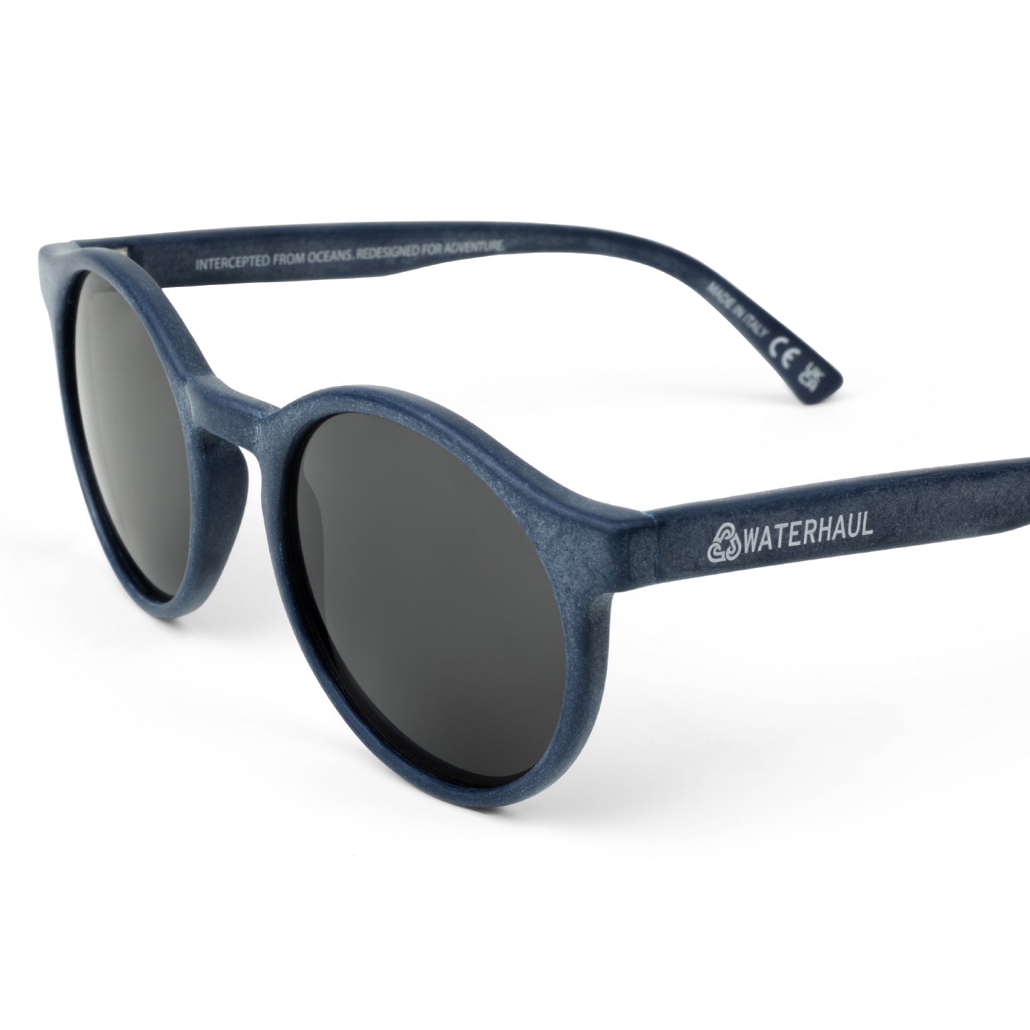Waterhaul sunglasses with rounded matte blue frames and dark polarized lenses, made from 100% recycled ocean plastic. Eco-conscious, adventure-ready eyewear designed for sustainable living and outdoor performance.