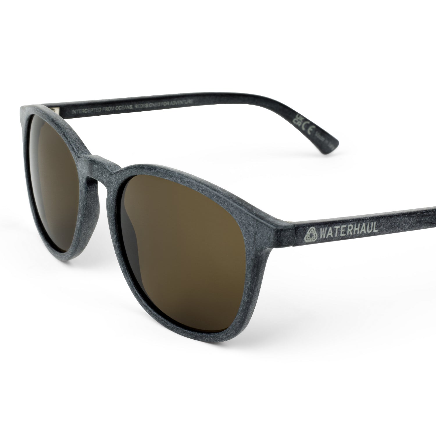 Waterhaul sunglasses with matte dark grey frames and brown polarized lenses, crafted from 100% recycled ocean plastic. Lightweight, sustainable eyewear with a subtle cat-eye silhouette, designed for active outdoor lifestyles.