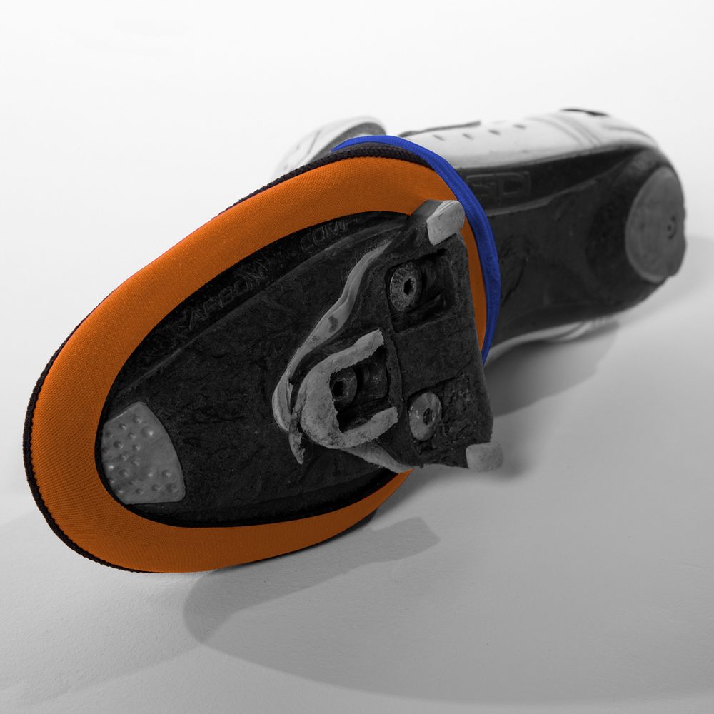 Bottom view of a cycling shoe with orange edged neoprene toe cap warmer attached to the sole