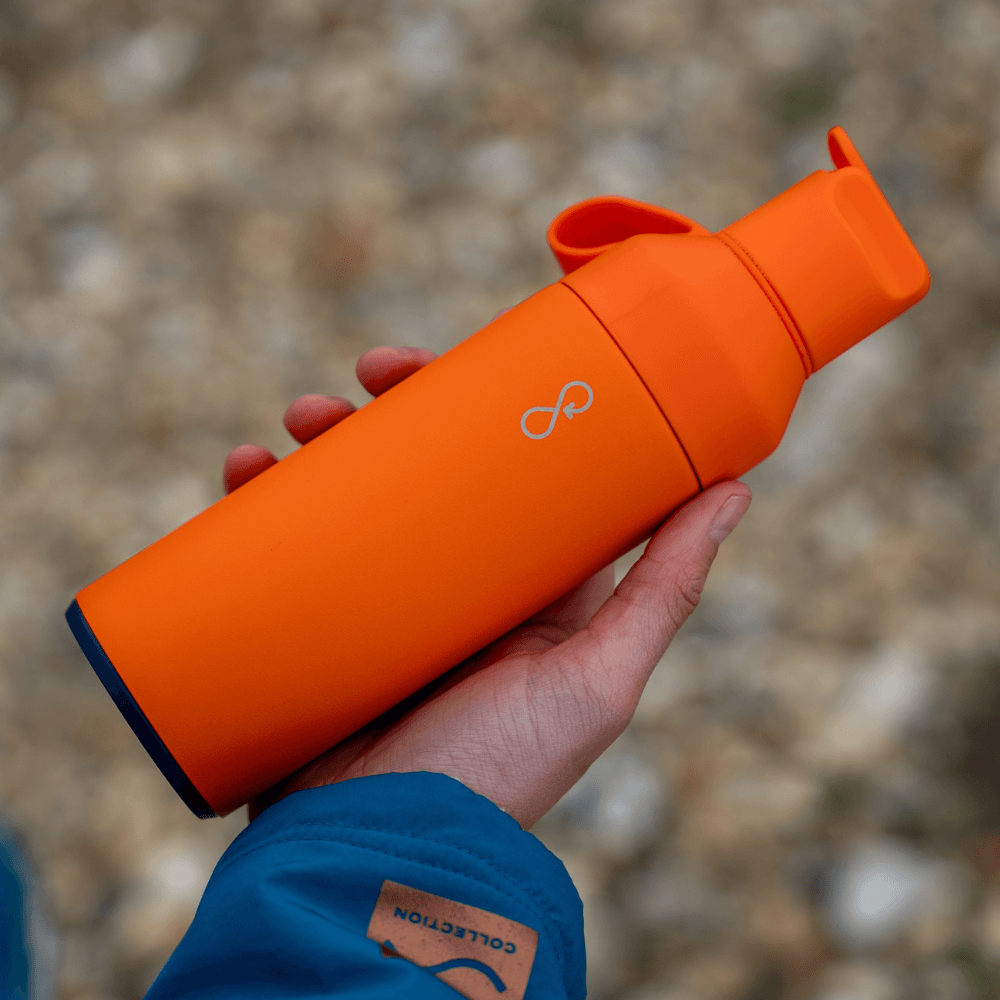 ZONE3 Ocean Bottle (500ml) in Sunshine Orange held in a person's hand against a blurred background.